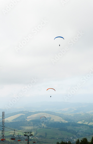 A man is flying on a paraglider in clouds and fog. Summer sports, active lifestyle, activity in mountains 