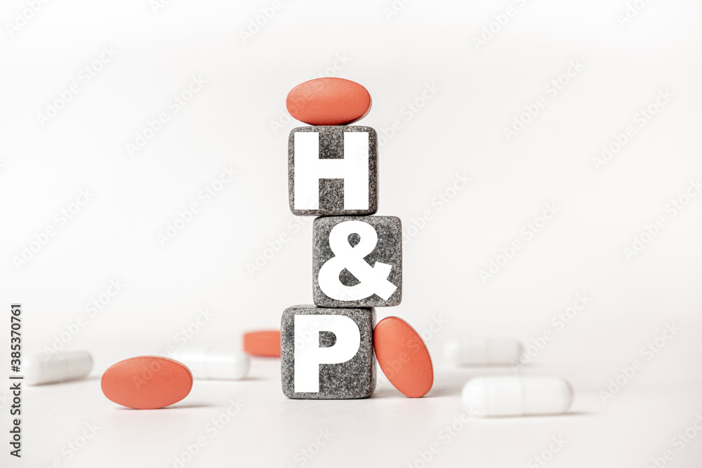 Obraz premium a group of white and red pills and cubes with the word HP History and physical examination on them, white background. Concept carehealth, treatment, therapy.