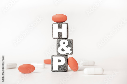 a group of white and red pills and cubes with the word HP History and physical examination on them, white background. Concept carehealth, treatment, therapy. photo