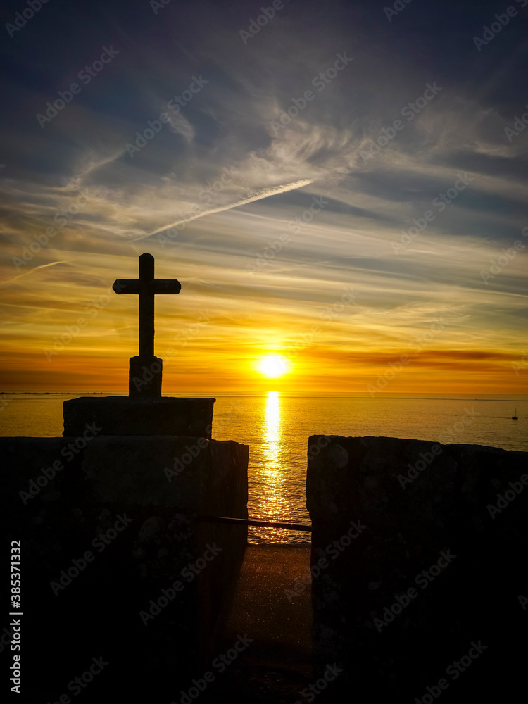 orange sunset or sunrise over the sea with the silhouette of a cross