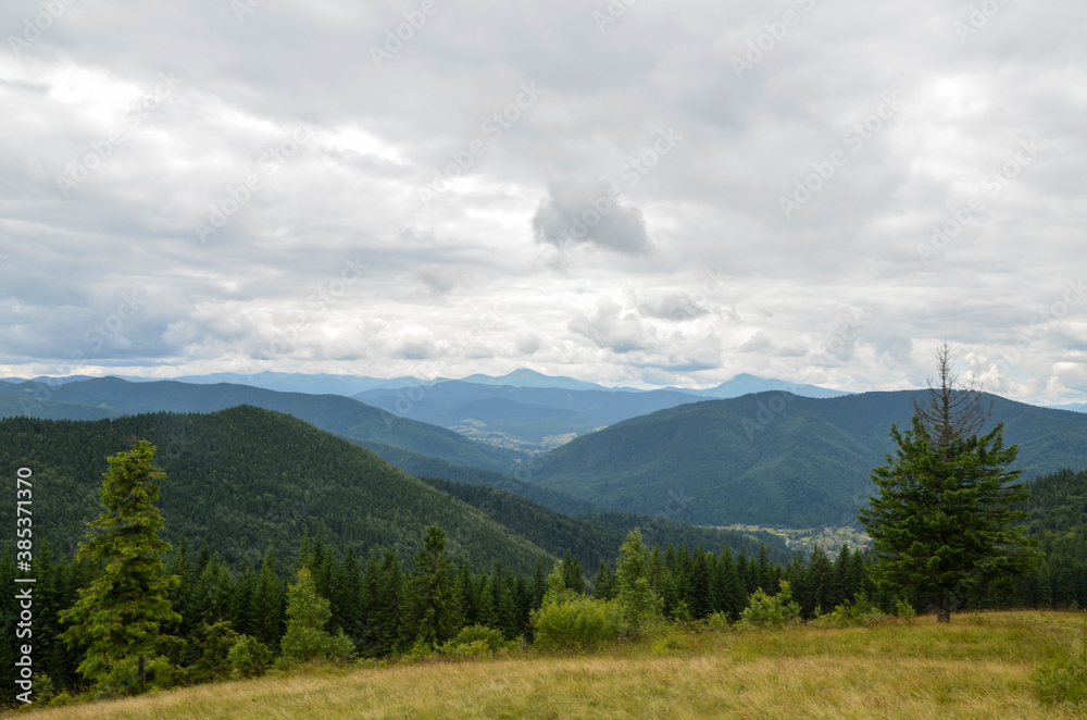 Carpathian covered forest and village, mountain ridge on background. Cloudy day in Carpathians, Ukraine Carpathian covered forest and village, mountain ridge on background. Cloudy day in Carpathians, Ukraine
