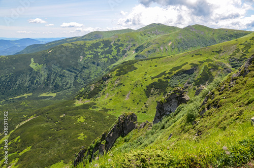 Sharp rock spires of mount Shpytsi on green hill.  Picturesque landscape of mountain valley. Chornohora ridge, Carpathian mountains, Ukraine photo