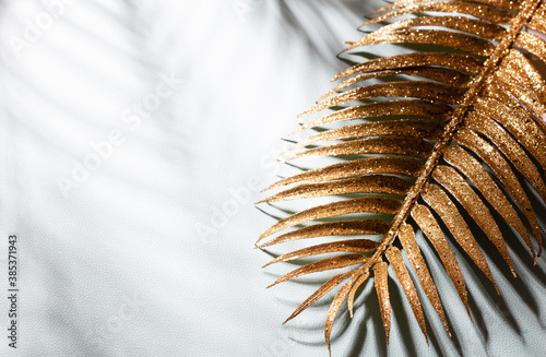 Gold palm leaves and shadows on a blue wall background.