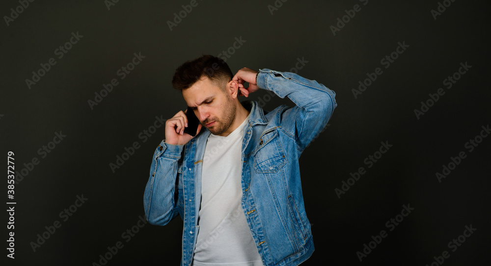 Handsome young man in a smart casual wear holding smart phone and looking at camera with smile Handsome young man in a smart casual wear holding smart phone and looking at camera with smile