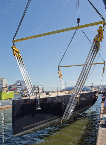Launch of a super sailing yacht. Lifting and hoisting with cranes. Shipbuilding industry. Harbor.