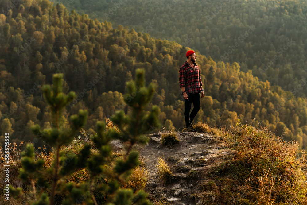 Traveler in the mountains. A man enjoys a beautiful view of the mountains. Man at sunrise in the mountains. A man is traveling in the Caucasus. Hiker at sunset in the mountains. Copy space