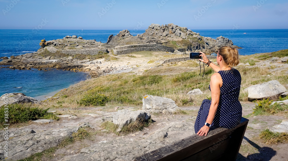 Woman photographing the Castro de Baroña in the province of La Coruña
