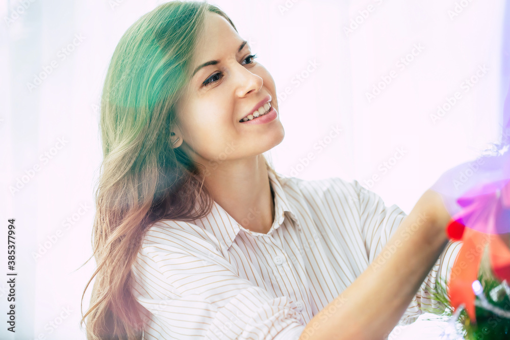 Close up photo of a beautiful happy young woman in a sweater is decorating the christmas tree at home and preparing to new year Close up photo of a beautiful happy young woman in a sweater is decorating the christmas tree at home and preparing to new year