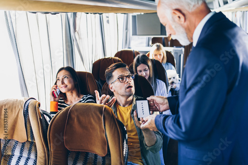 Young male traveler showing  e-ticket on mobile phone screen to a bus driver.