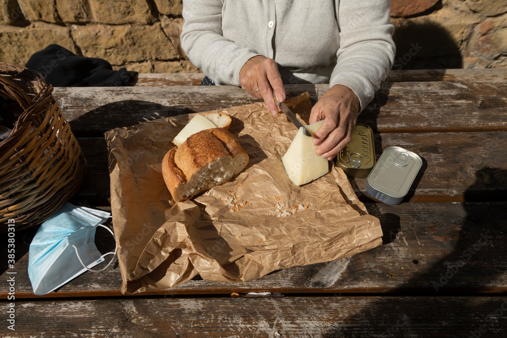 Φωτογραφία A senior woman, cuts slices of goat cheese at the mountain hut of the fountain of Artica, in Luesia, Spain