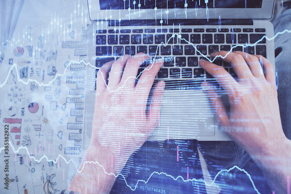 Double exposure of man's hands typing over laptop keyboard and forex chart hologram drawing. Top view. Financial markets concept. Double exposure of man's hands typing over laptop keyboard and forex chart hologram drawing. Top view. Financial markets concept.