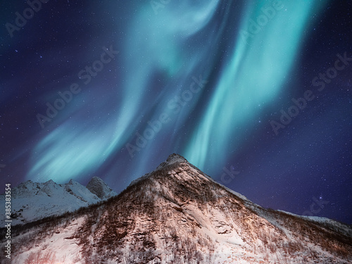 Sky background with northern lights. Aurora borealis on Lofoten islands, Norway. Northern lights above mountains. Night winter landscape with aurora. Natural background in the Norway.