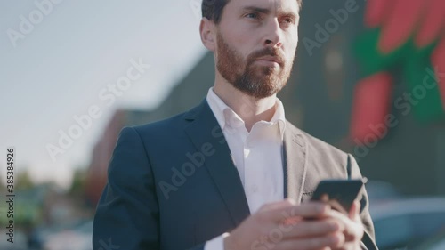 Close up of young attractive businessman walking use smartphone at city center. Handsome man messagen stylish. Employment technology suit. Slow motion photo