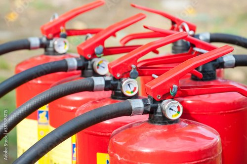 Many red powder fire extinguishers with pressure gauge. Detail of fire extinguishers. Сheck pressure guage. Red, green or yellow level.