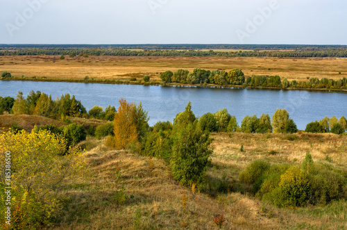 Autumn landscape with trees, hills and a river. Typical Russian view in rich golden and green colors.