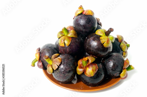 Mangosteen is the king of fruits native to Southeast Asia.
In the photo there is a group of fruits on a plate. White background.