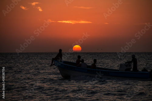 sun setting on the horizon the water of the caribbean sea and a boat with people