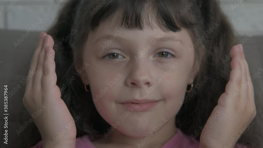 Hide child face with hands. A happy child with big eyes shows her face between her hands in the room. Hide child face with hands. A happy child with big eyes shows her face between her hands in the room.