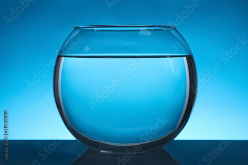 Round fish bowl filled with water on blue background