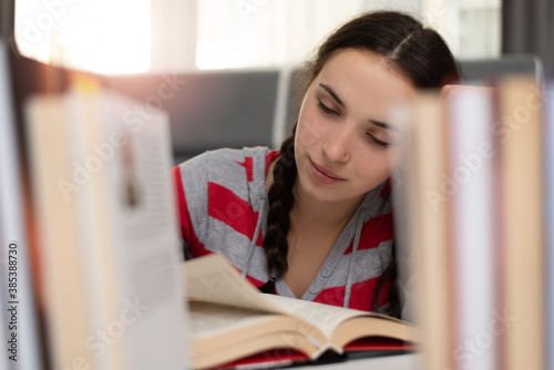 Social distancing student concept, education at home. High school girl doing homework at home in private library. The school is closed during Coronavirus Covid-19.