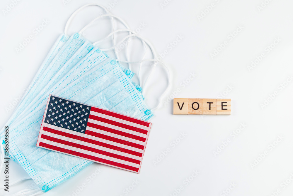 Obraz premium Vote now. Voting concept for the November 3 elections. Medical protective masks and USA flag on white background.