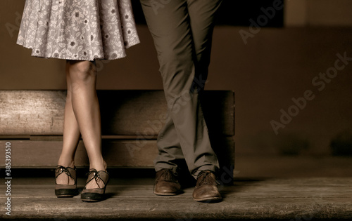 Crossed legs of a couple standing on a wooden bench.