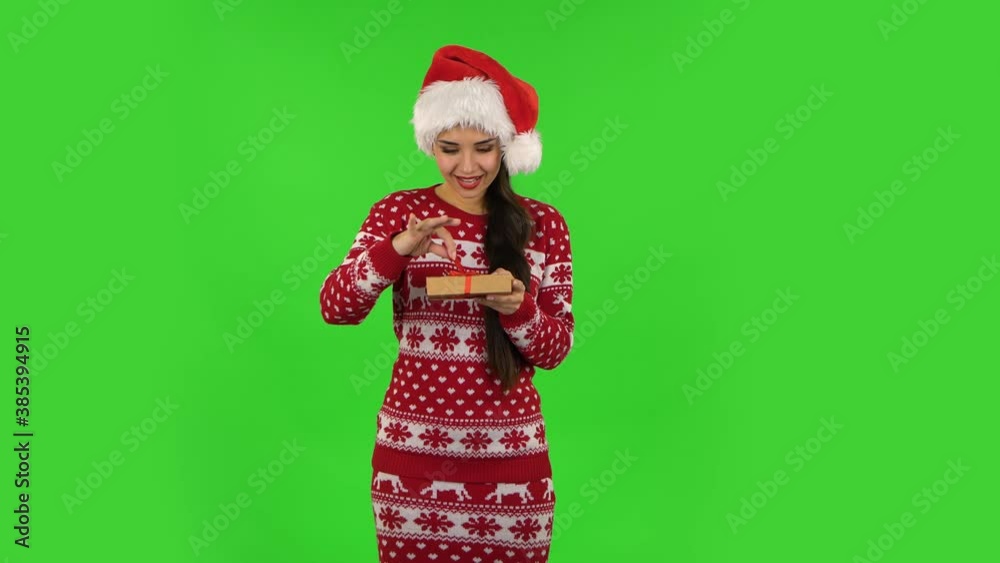 Sweety girl in Santa Claus hat is opening the gift and rejoicing. Green screen Sweety girl in Santa Claus hat is opening the gift and rejoicing. Green screen