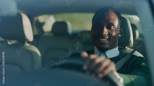 Funny young african american man smiling driving car with passenger. Feel happy at sunlight. Automobile businessman traffic transportation. Slow motion