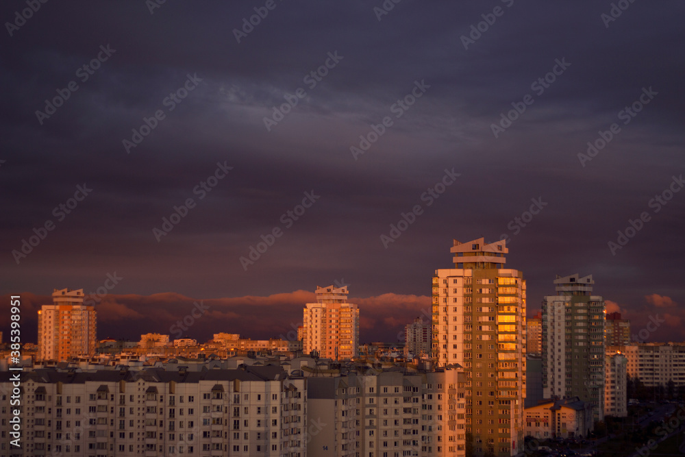Fototapeta premium big city residential houses with sunset warm light and dark clouds