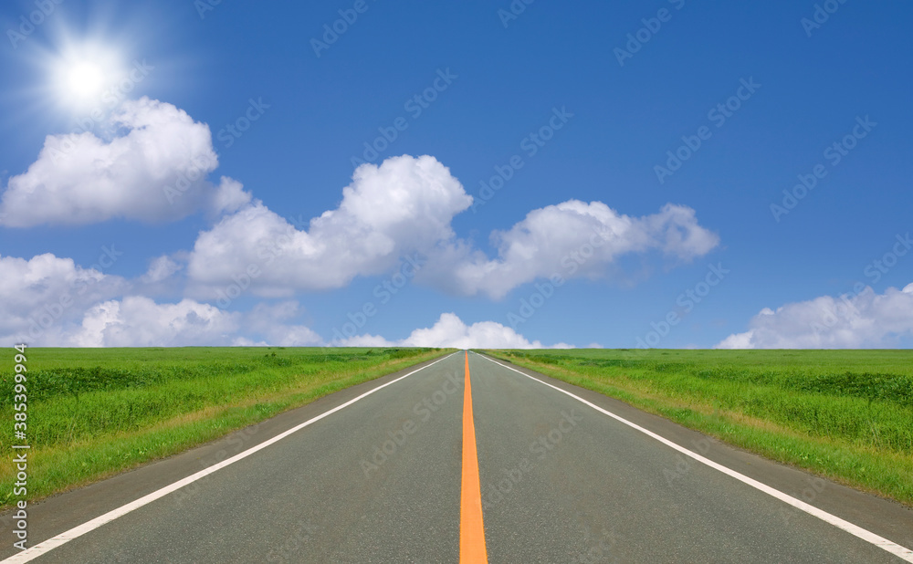 草原の直線道路と雲と太陽