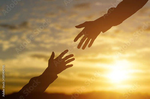 Картината върху платно Silhouette of giving a helping hand, hope and support each other over sunset background