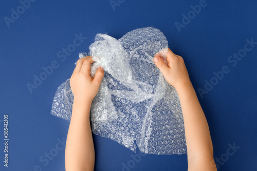 Canvas-taulu Hands popping a bubble wrap on classic blue background, antistress therapy conce