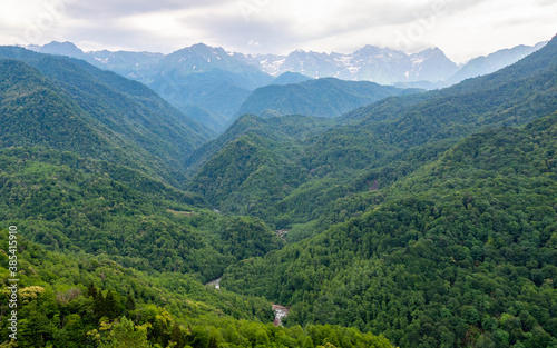 Wild landscape of Georgian mountains. Green trees lover and snow in the hills