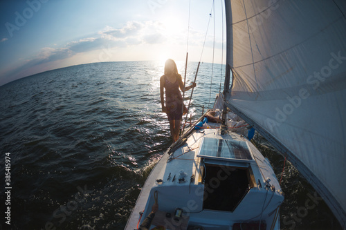A girl in a dress stands on a sailing yacht