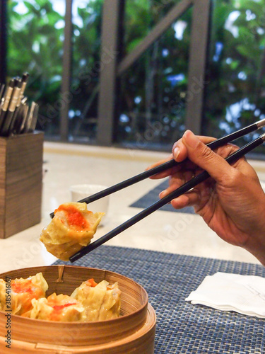 Picking up a siew mai (dim sum) with chopsticks