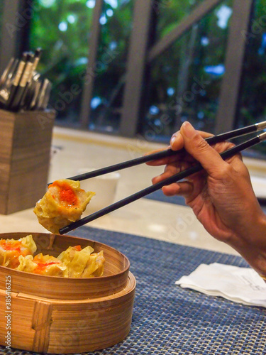 Picking up a siew mai (dim sum) with chopsticks