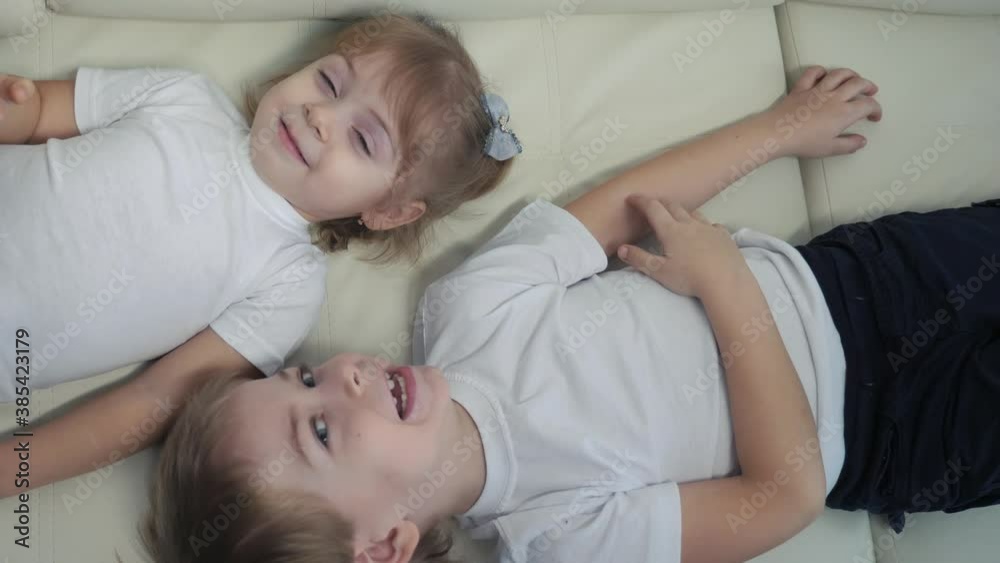 happy family kids brother and sister play on the couch laugh tickle each other. children little boy and girl play lifestyle indoors laughing and fun happy childhood happy family kids brother and sister play on the couch laugh tickle each other. children little boy and girl play lifestyle indoors laughing and fun happy childhood