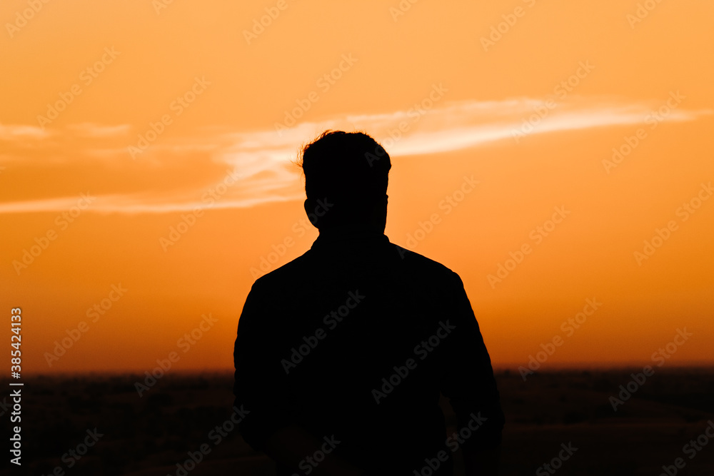 Silhouette of an Indian business man standing in front of the sun during the sunset Silhouette of an Indian business man standing in front of the sun during the sunset