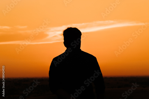Silhouette of an Indian business man standing in front of the sun during the sunset