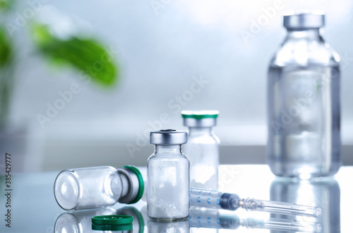 Powdered drug in vial as vaccine dose flu shot along with syringe for injection treatment on medical table. Vaccination or immunization care concept background.