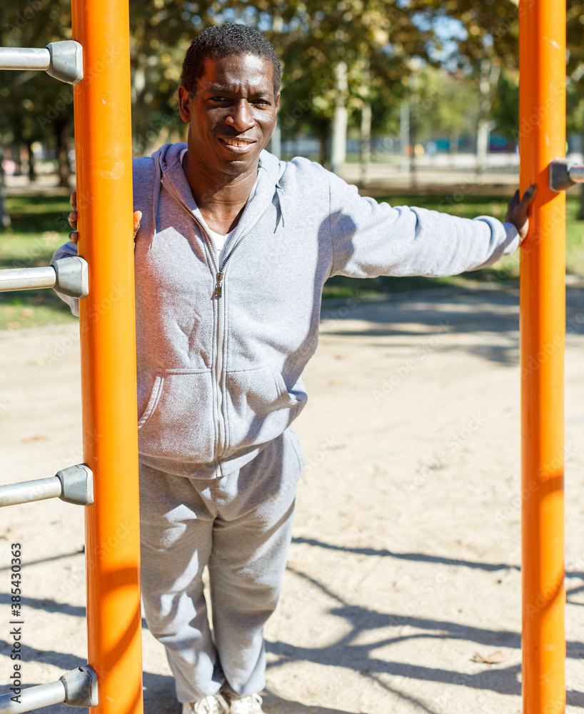Fototapeta premium Athletic young male training different exercises at chin-up bar in park outdoor