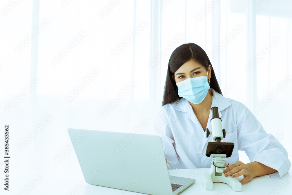 Beautiful woman scientist using a microscope And laptop or notebook computer to work. Beautiful woman scientist using a microscope And laptop or notebook computer to work.