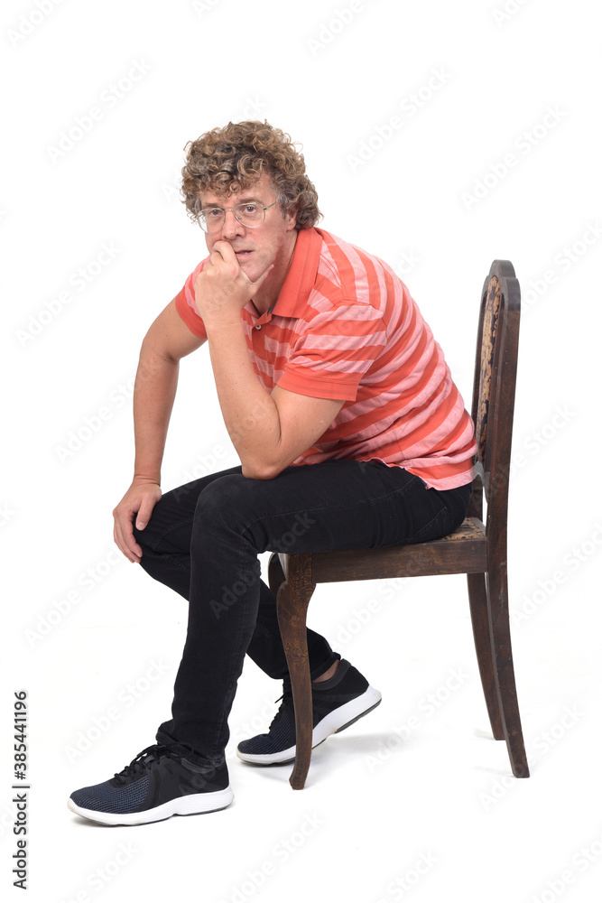 full portrait of a curly man sitting sideways on white background, thinking