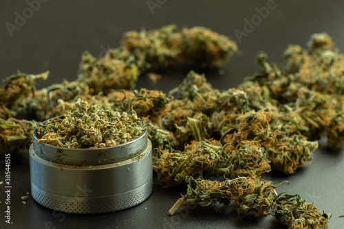 Marijuana buds on background with blur, grinder with cannabis, copy space photo