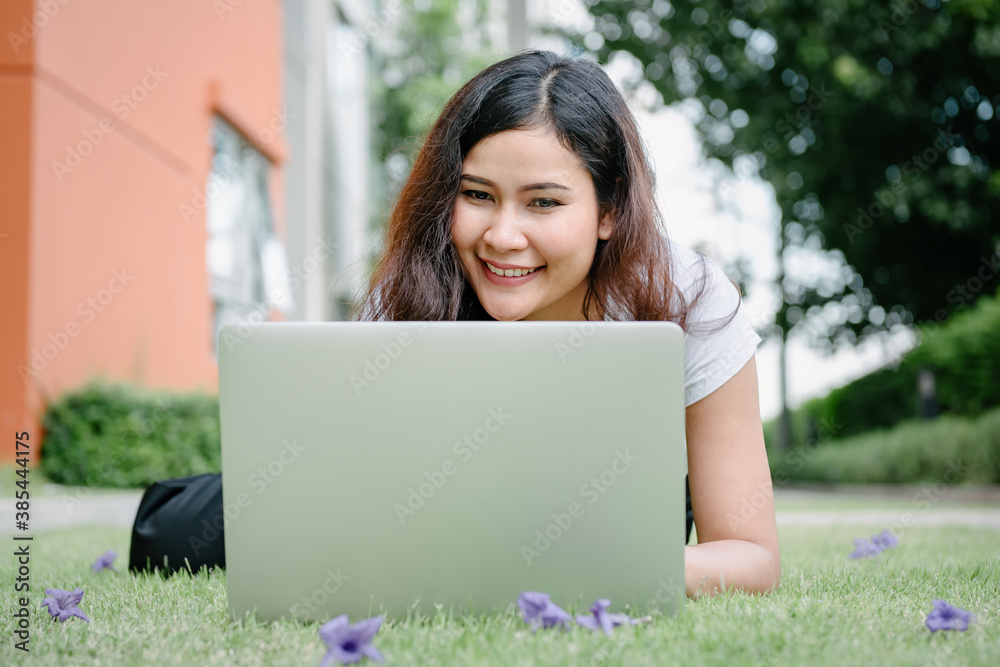 Beautiful Woman Relaxing and Using Laptop While Laying on Grass Field, Asian Woman Working Online on Laptop Device and Joying .Social Media. Relaxation Leisure Activities Lifestyles/Work at Home. Beautiful Woman Relaxing and Using Laptop While Laying on Grass Field, Asian Woman Working Online on Laptop Device and Joying .Social Media. Relaxation Leisure Activities Lifestyles/Work at Home.
