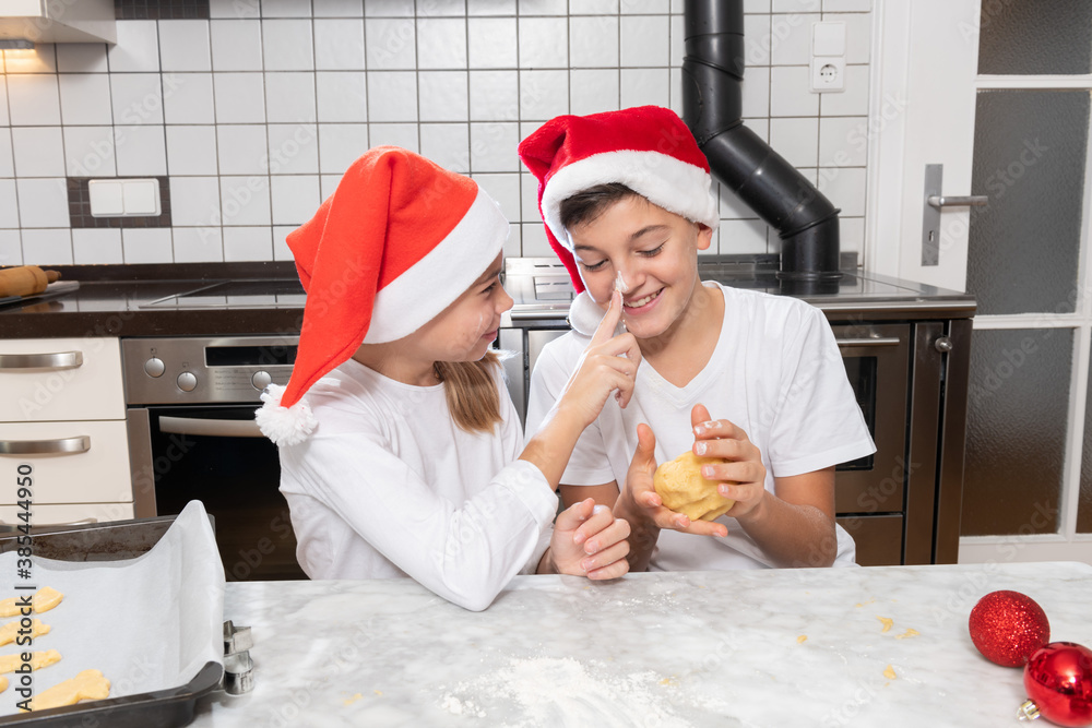 Fototapeta premium Gemeinsames backen von Plätzchen in der Weihnachtsbäckerei, Junge und Mädchen haben viel Spaß bei der Vorbereitung in der Küche.