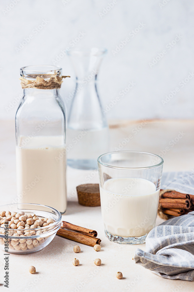 Chickpea vegetarian milk in a bottle and glass and raw chickpeas on light stone background. Lactose free non dairy products. Healthy vegan food concept. Chickpea vegetarian milk in a bottle and glass and raw chickpeas on light stone background. Lactose free non dairy products. Healthy vegan food concept.