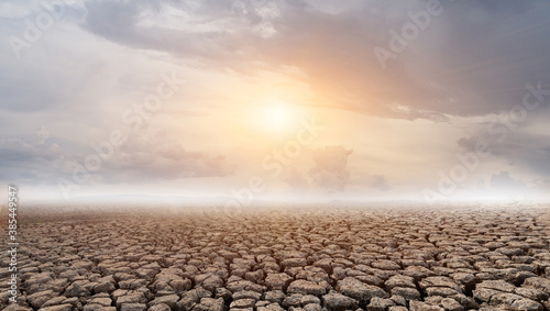 Cracked and dry soil in arid areas landscape with sun and cloud