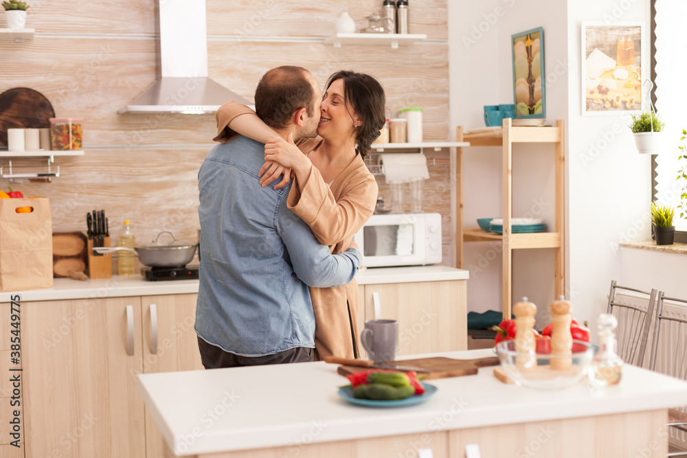 Tender couple dancing in kitchen and fresh vegetables on table. Wife and husband love, romance, tender moment, fun and happiness at home, togetherness music cheerful and smile