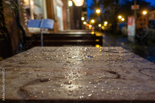 Regentropfen auf einem leeren Tisch des leeren Freisitzes eines asiatischen Restaurants in Berlin
